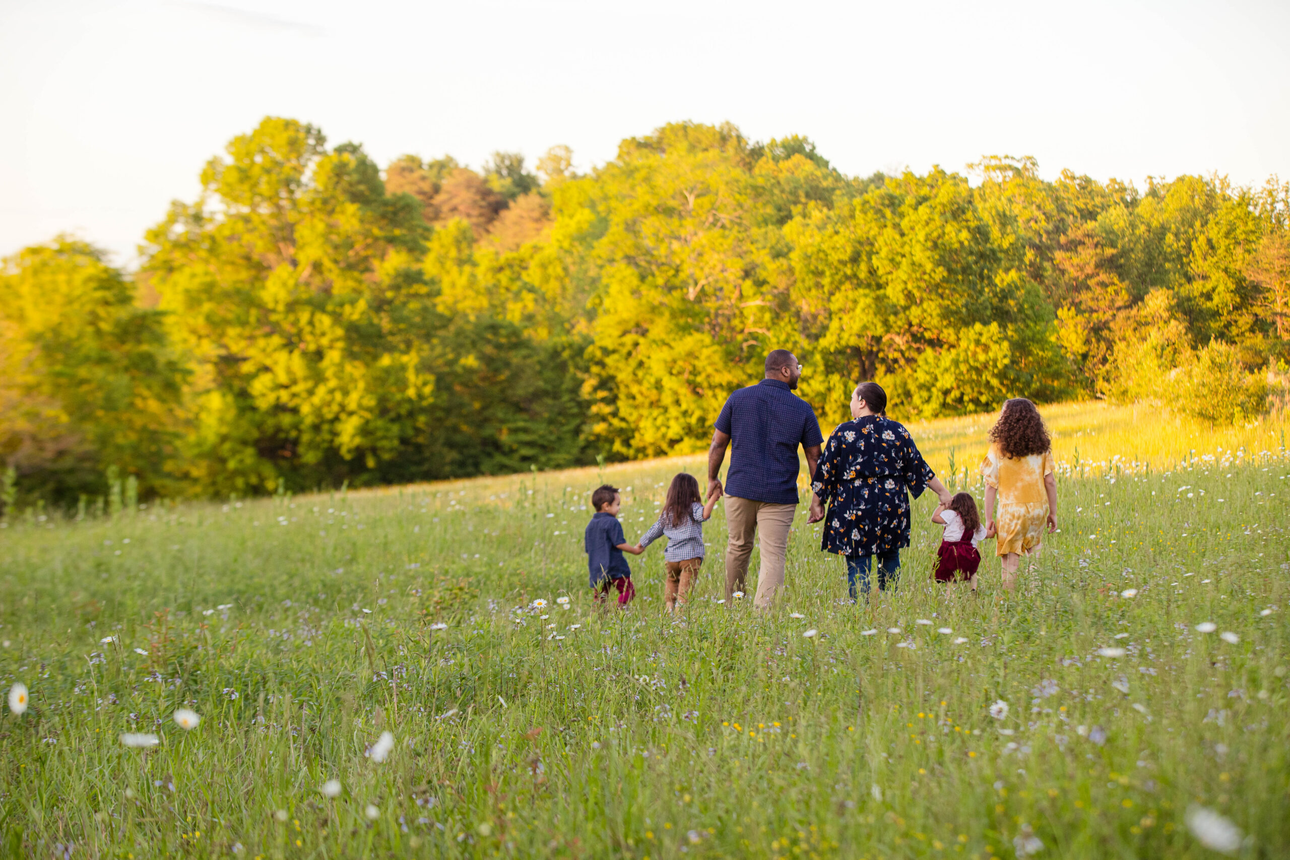 D. Colton Baker with his wife and five children walking through a field at sunset